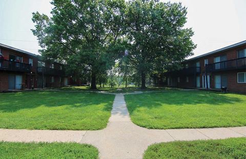 a walkway between two apartment buildings with grass and trees