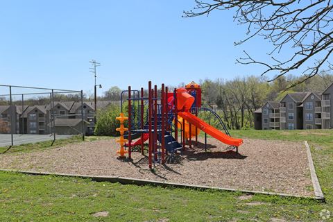 a playground at a park with houses in the background