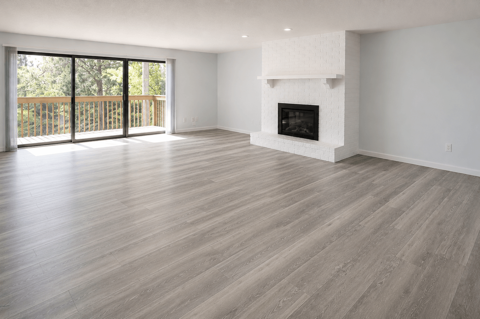 A large, empty room with a fireplace and sliding glass doors.