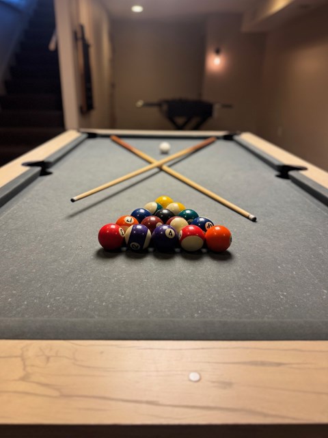 A pool table with a variety of balls and two cues.
