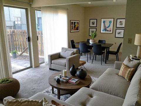 A living room with a grey couch, a coffee table, and a dining table with chairs.