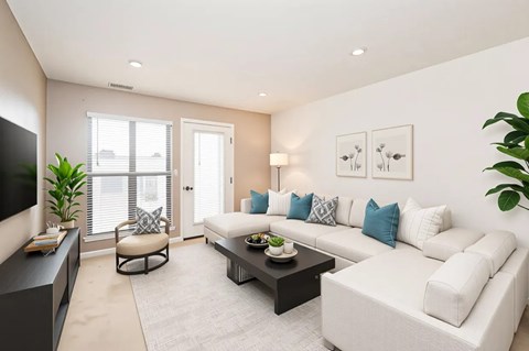 A living room with a white couch, a black coffee table, and a flat-screen TV.