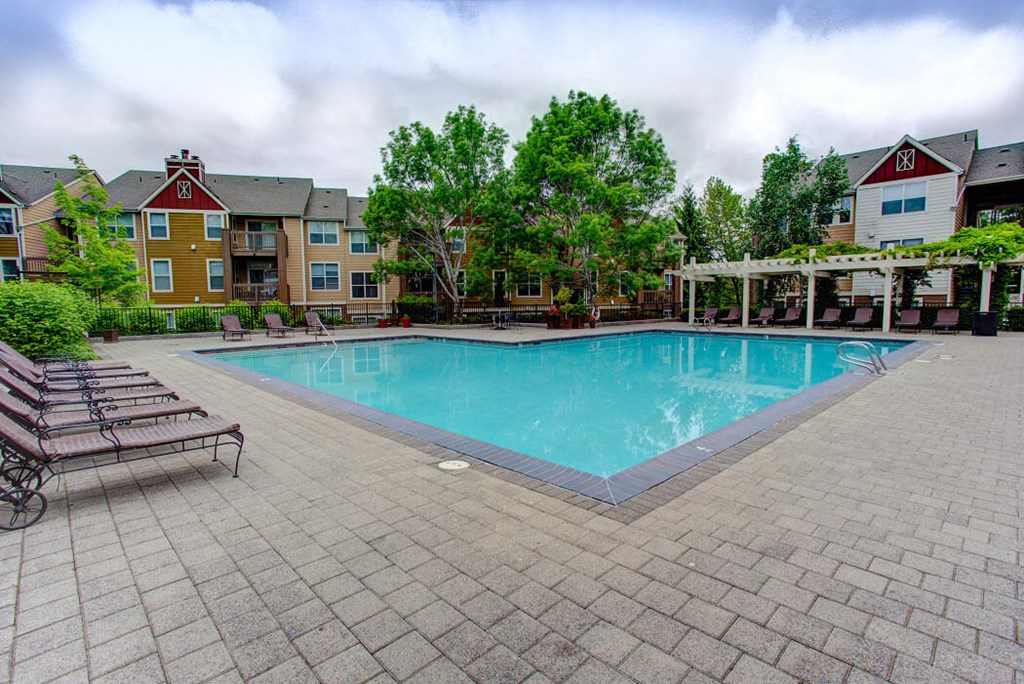 a swimming pool with benches around it next to a apartment building
