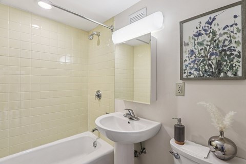 A white sink in a bathroom with a white bathtub and a white towel.