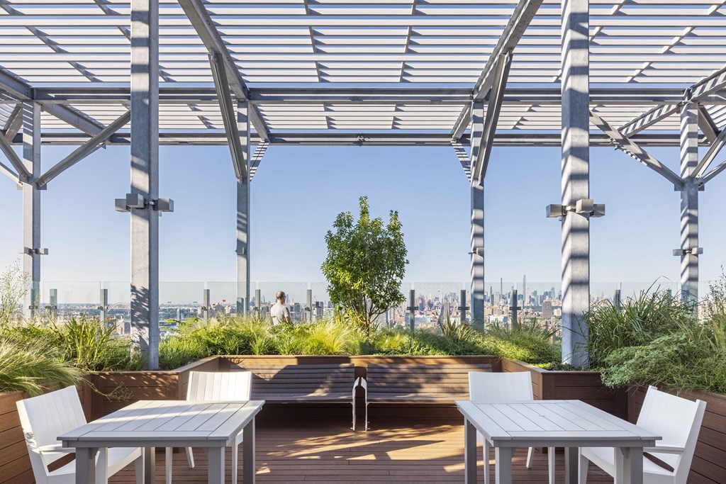a roof deck with tables and chairs and a view of the city