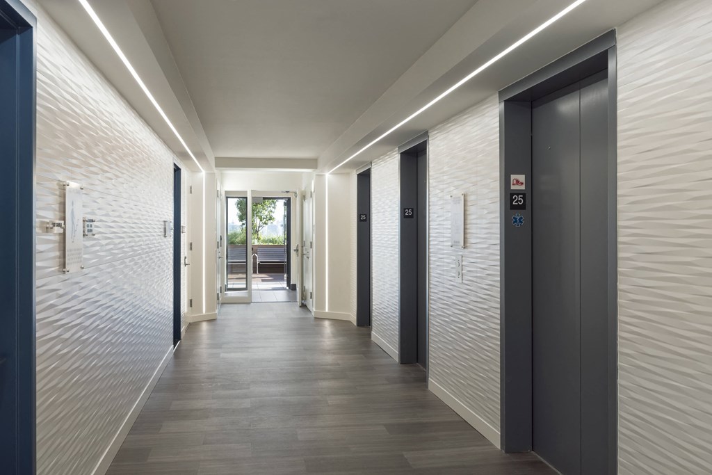 a row of elevators in a corridor with white brick walls and wood floors