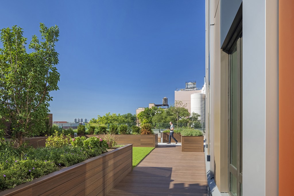 a roof terrace with a garden and a person sitting on a bench