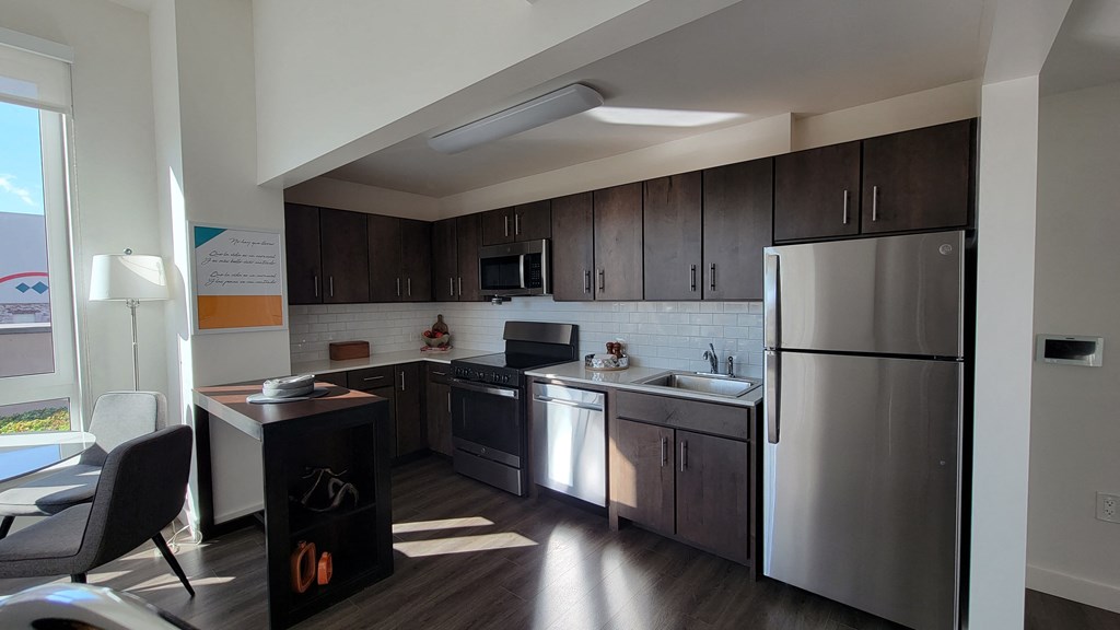 an apartment kitchen with stainless steel appliances and dark wood cabinets