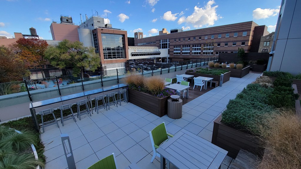 a roof terrace with tables and chairs and a building in the background