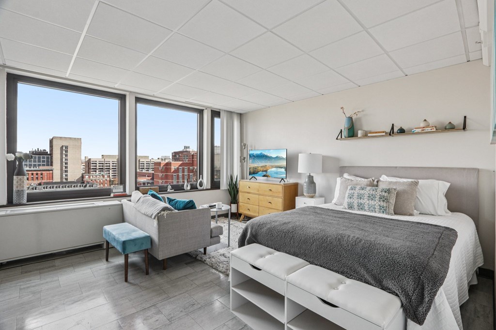 A bedroom with a large bed and a window overlooking a cityscape.