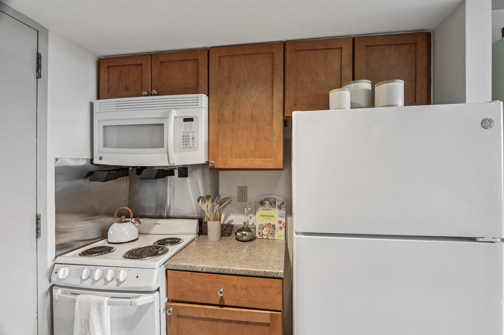 A white refrigerator stands in a kitchen with wooden cabinets.
