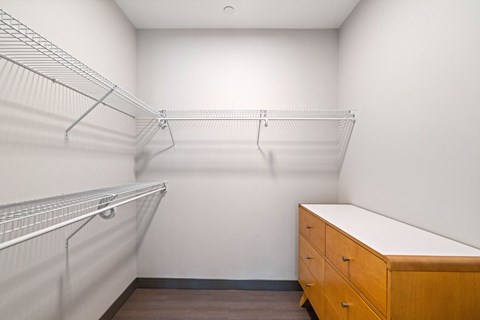 A walk-in closet with a wooden bench and metal shelving.