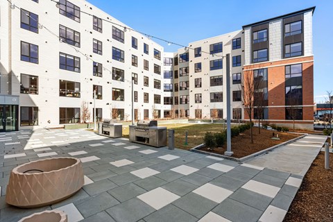 A courtyard with a checkered floor and a white and black building in the background.