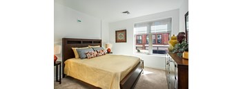 A bedroom with a bed, nightstand, and a window with blinds.