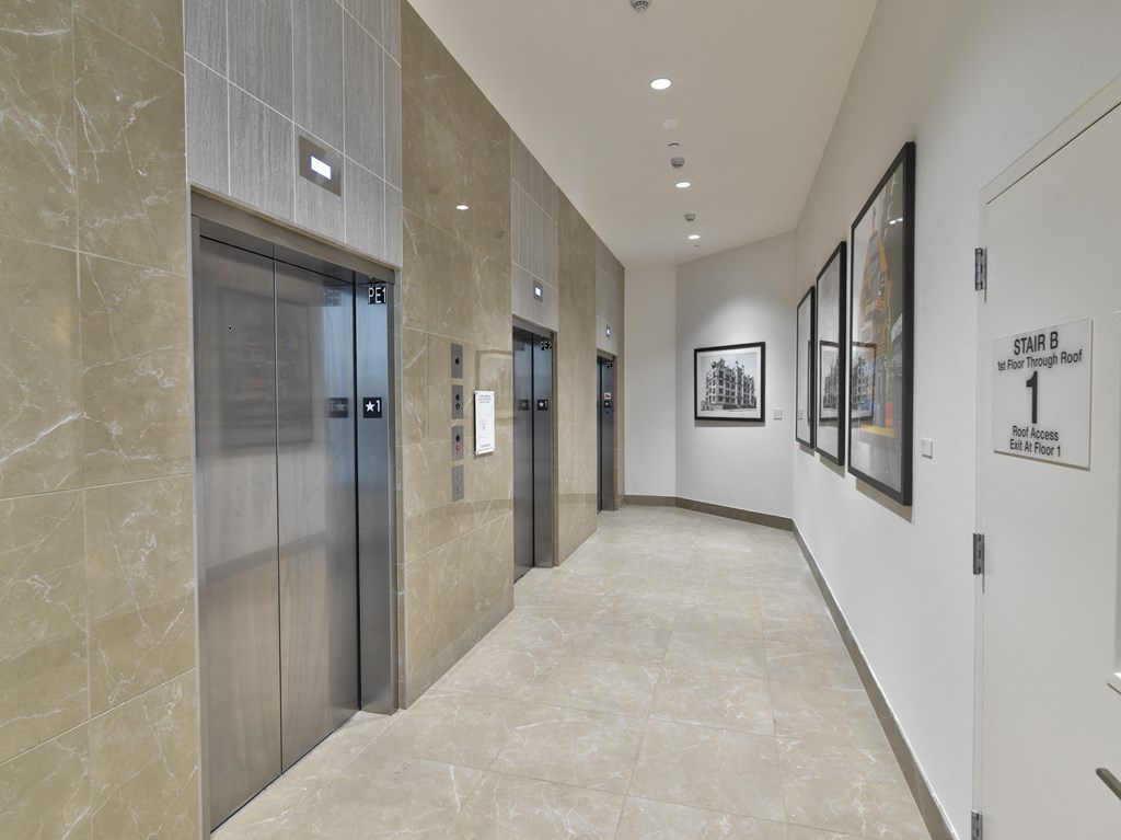 a hallway with elevators and paintings in a building