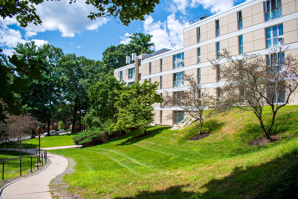 a large building on a grassy hill with trees