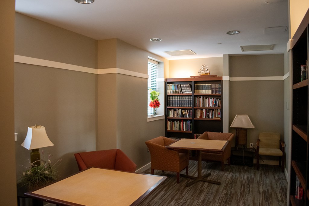 a room with a table and chairs and a bookcase with a window