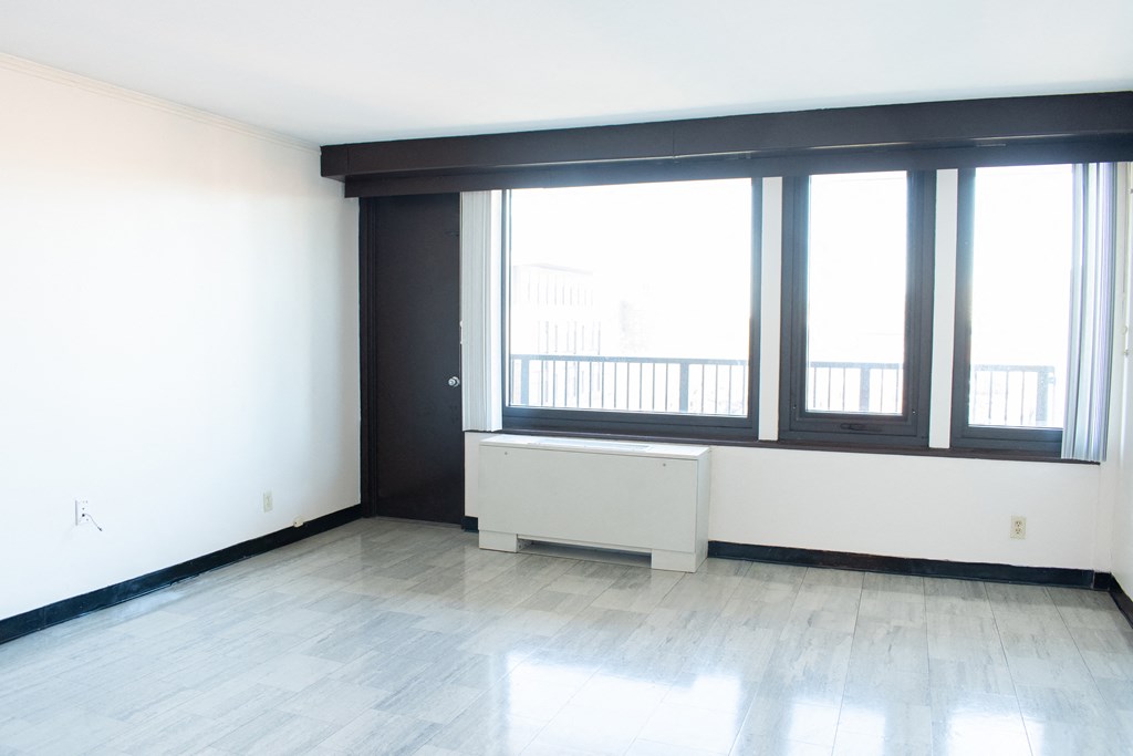 A large empty room with a window seat and a door.