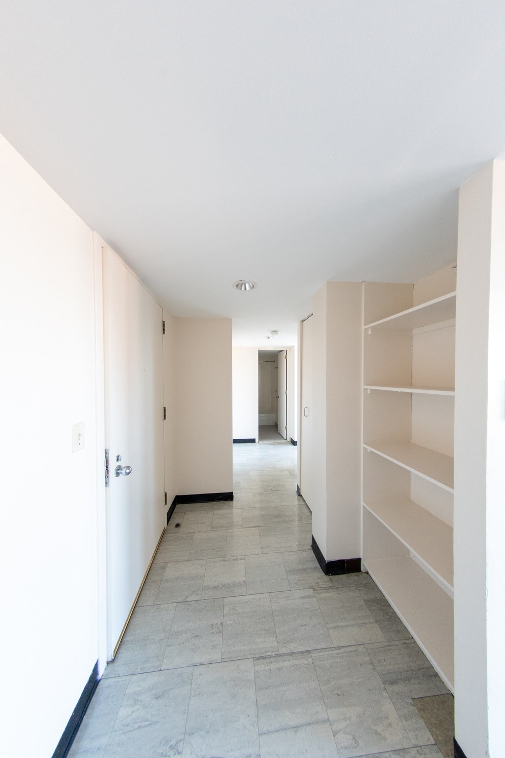 A long hallway with a tile floor and white walls.