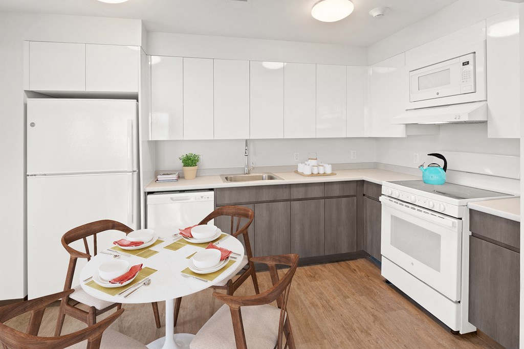 a kitchen with white appliances and a small table with chairs