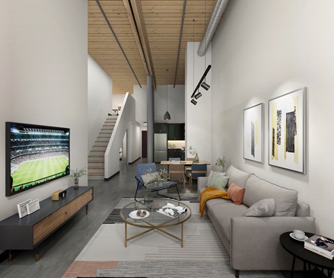 A modern living room with a grey couch, a coffee table, and a television displaying a soccer game.