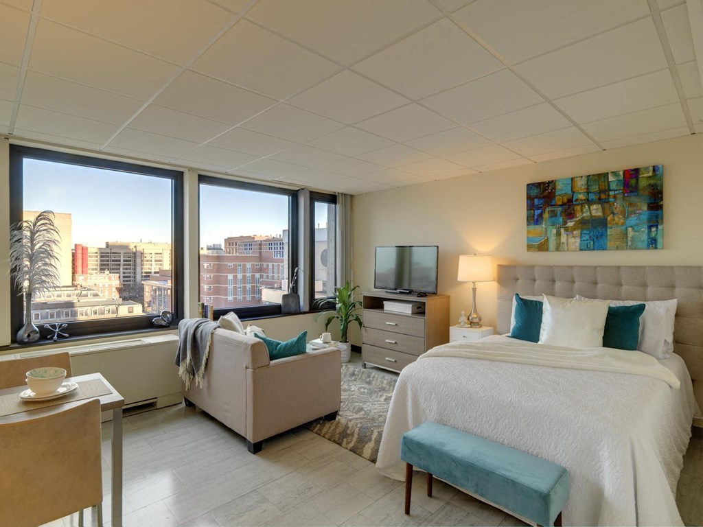 a bedroom with a bed and a couch and windows