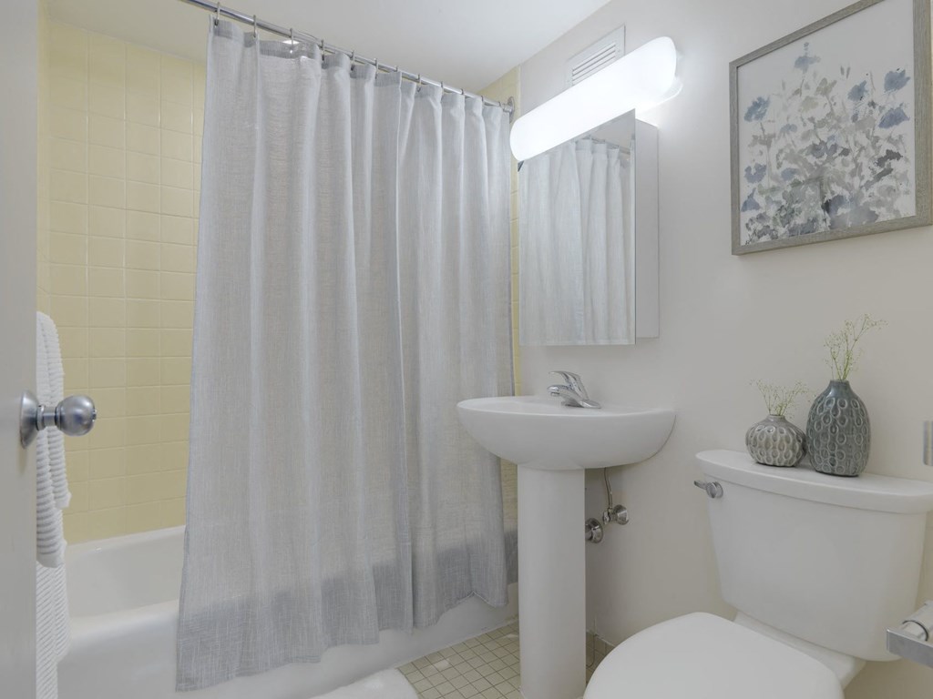 a white bathroom with a shower curtain and a toilet and a sink
