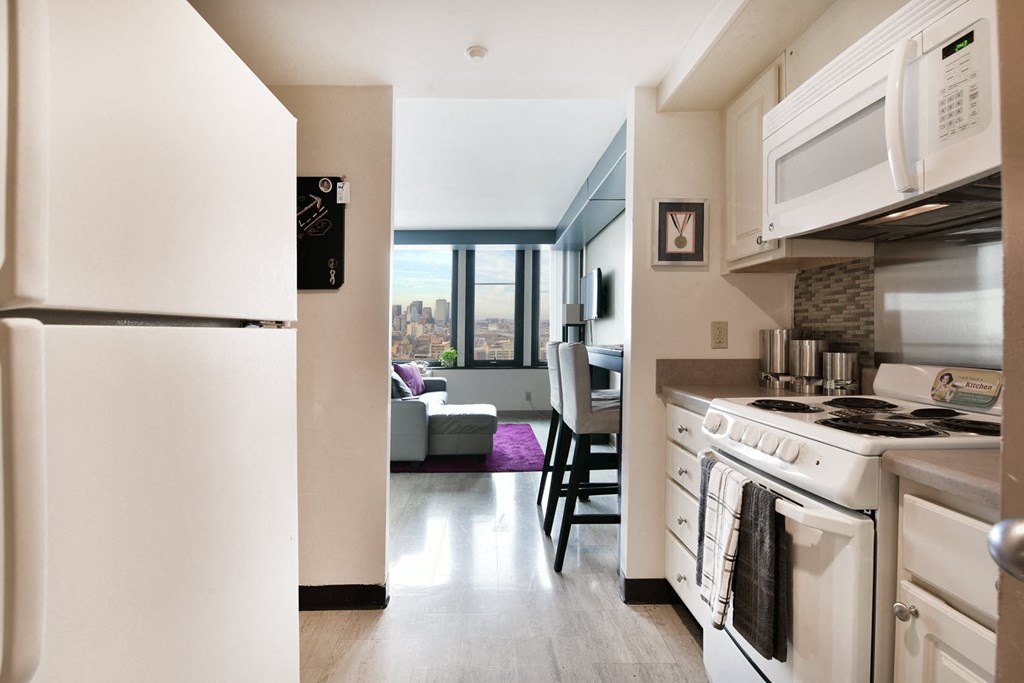 a kitchen and living room with a stove refrigerator and microwave