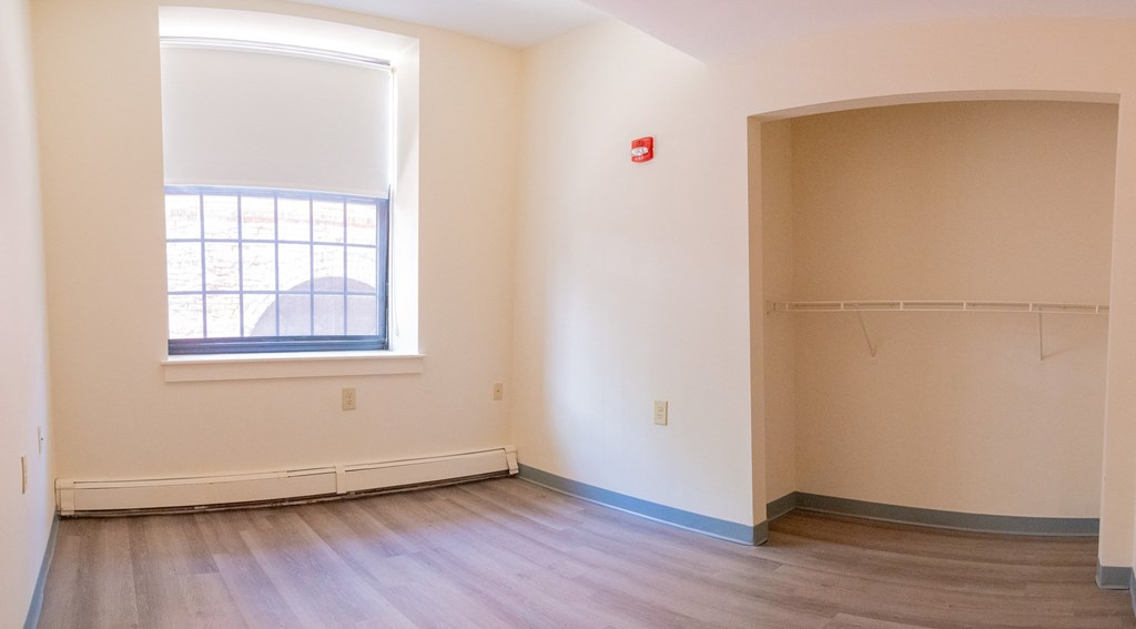 an empty room with wood floors and a large window