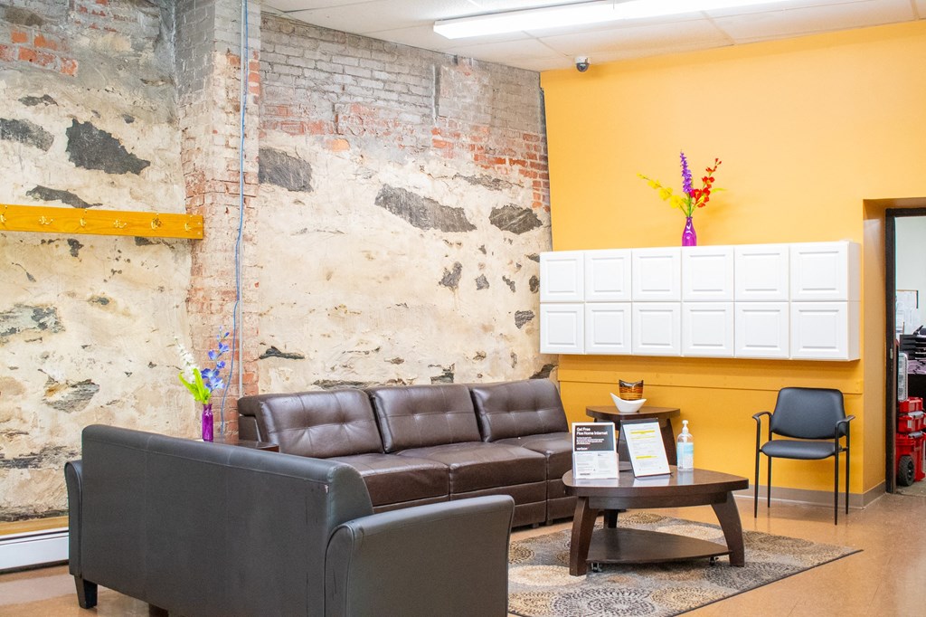 a living room with a couch and chair in front of a wall with a exposed brick wall
