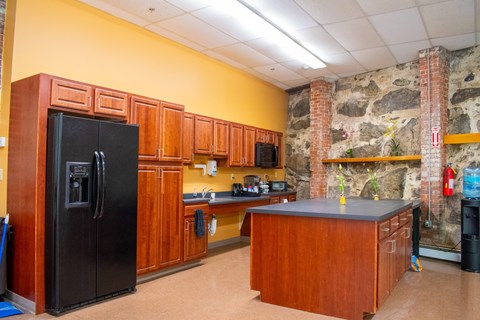 a kitchen with a refrigerator and a counter and a stone wall