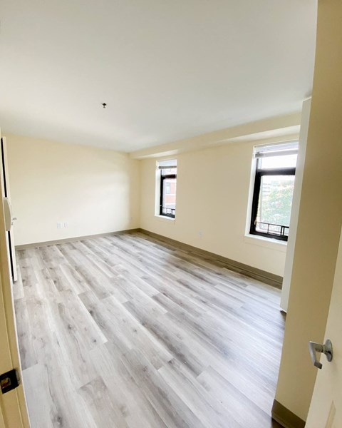 the living room of a new home with wood flooring and a window