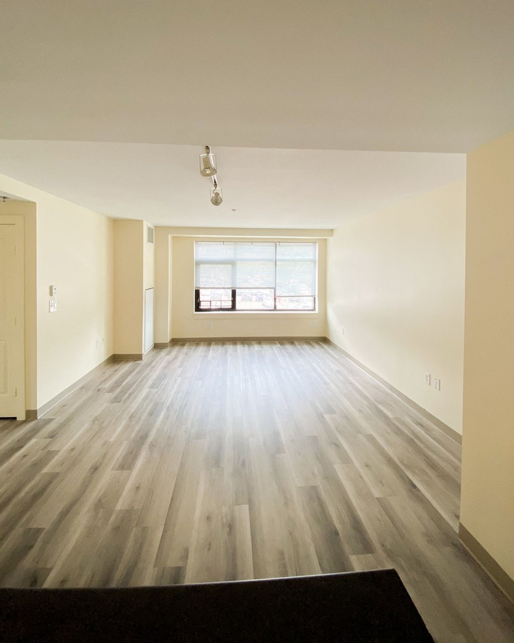 an empty living room with wood floors and a window