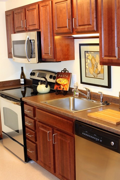 A kitchen with wooden cabinets and a black dishwasher.