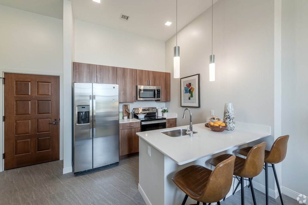 private kitchen with stainless steel appliances and a white island with stools