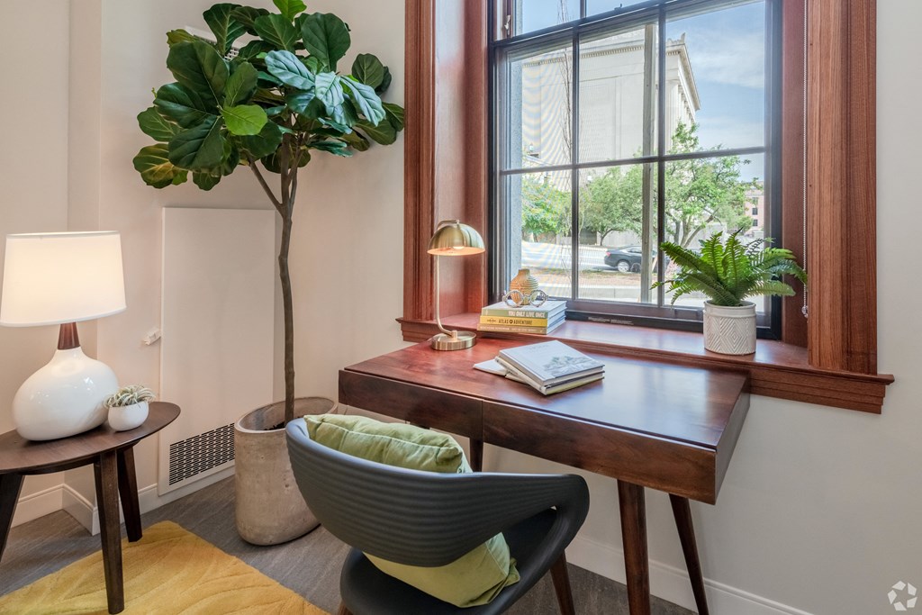 a home office with a window and a desk with a chair and a plant