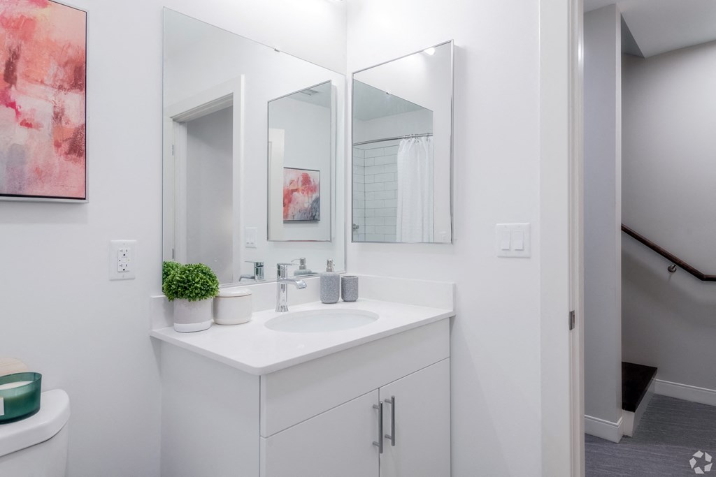 a white bathroom with a sink and three mirrors
