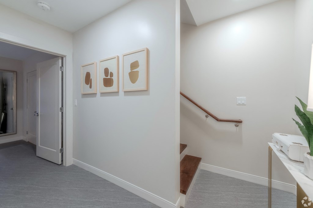 a hallway with a staircase and paintings on the wall