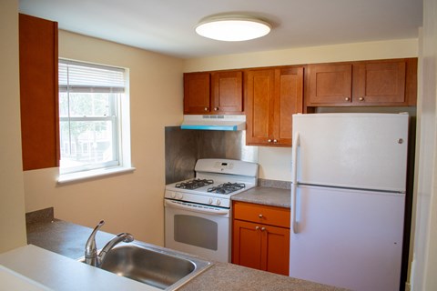 A kitchen with a white refrigerator, stove, and sink.