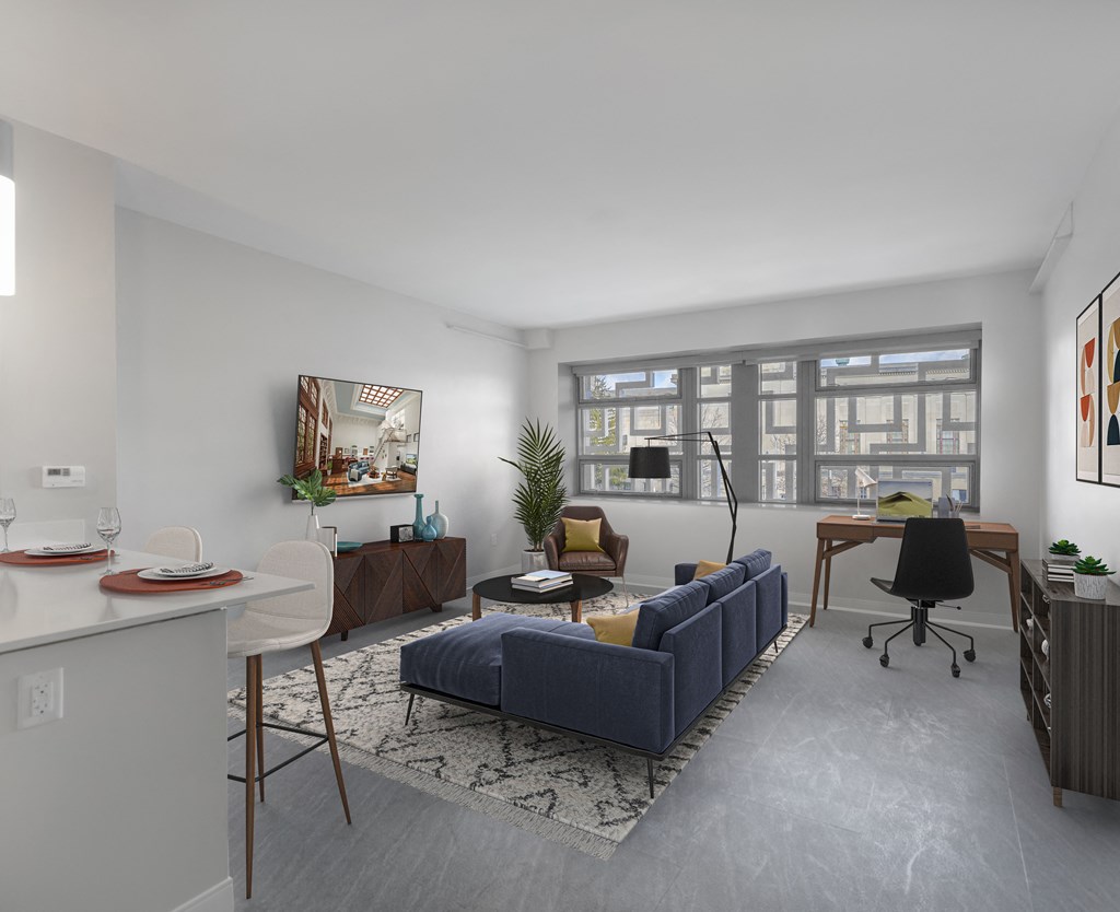 a living room with a blue couch and a desk and a window