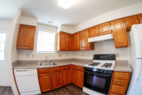 A kitchen with wooden cabinets and a white dishwasher.