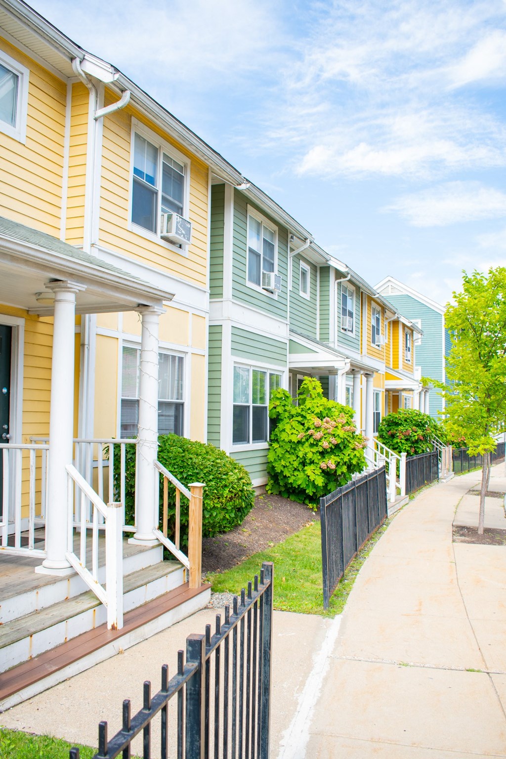 a row of townhomes with yellow and green siding