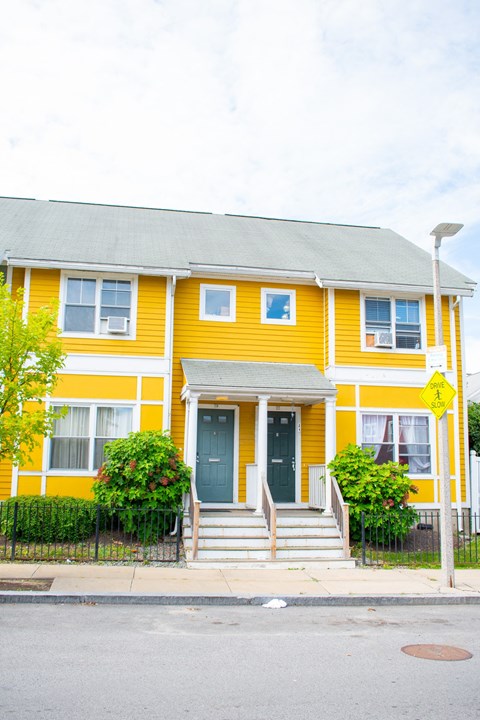 a yellow house with green bushes in front of it