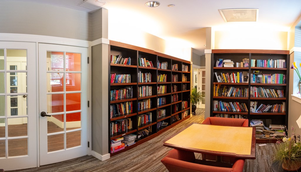 a library with a table and chairs in front of a bookshelf