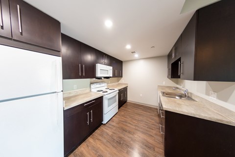 A kitchen with dark wood cabinets and a white fridge.