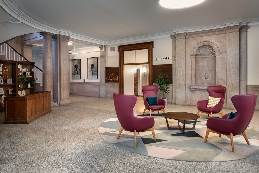 a lobby of a building with chairs and a table