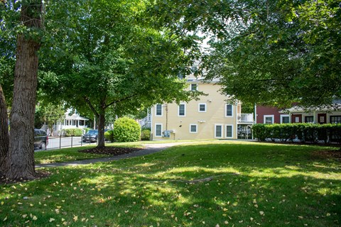 a grassy area with trees and buildings in the background
