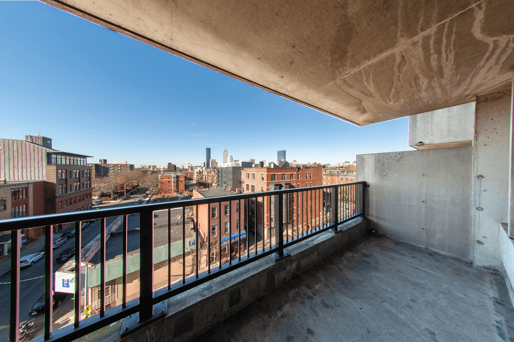 A balcony with a metal railing overlooks a cityscape.