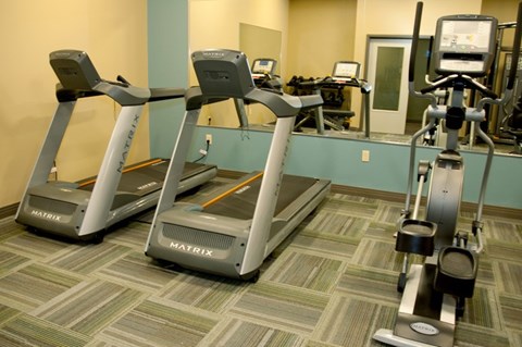 Two treadmills in a gym with a green wall in the background.