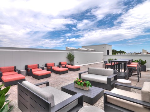 A patio with red and grey furniture and a white building in the background.